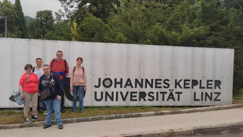 People First als Gruppe vor dem Schild der Johannes Kepler Universität in Linz. 