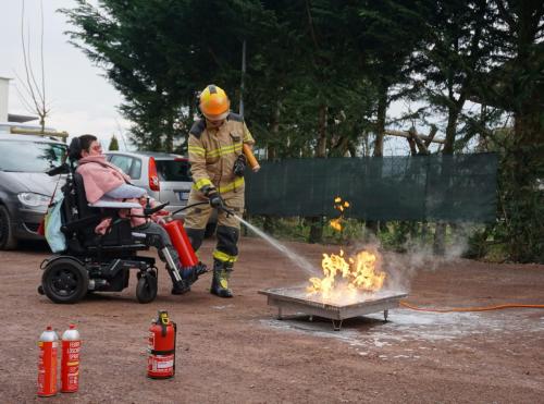 Brandschutz·kurs mit Rollstuhl das Feuer löschen